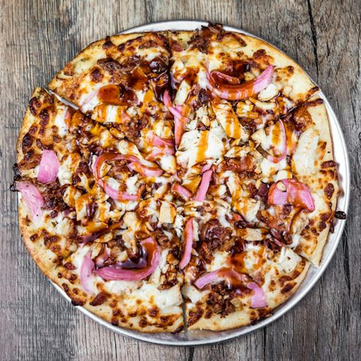 an overhead shot of a bbq chicken pizza on a wooden table