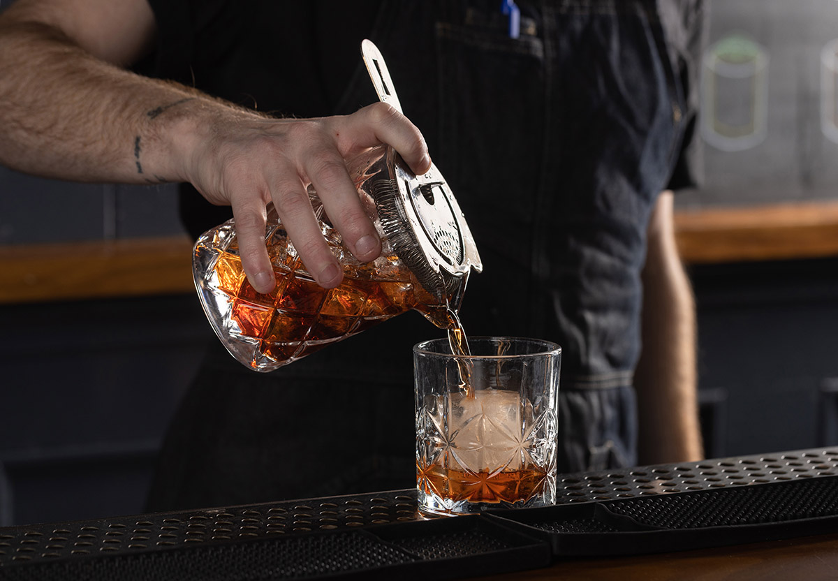 a hand holding a glass of beer on a table