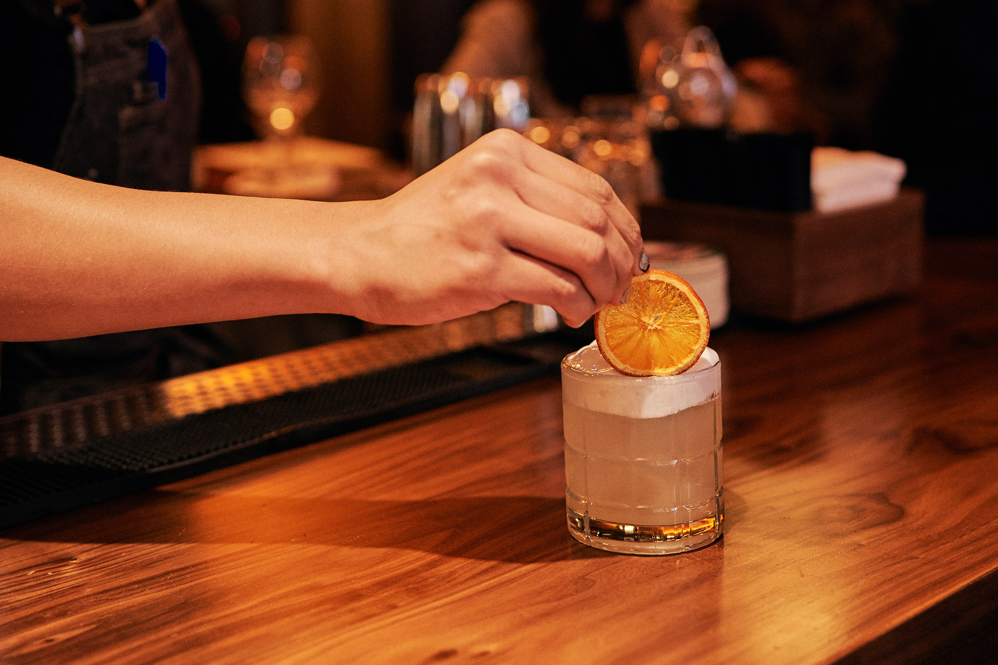 bartender putting an orange slice on Liberty Bell cocktail at the Independent