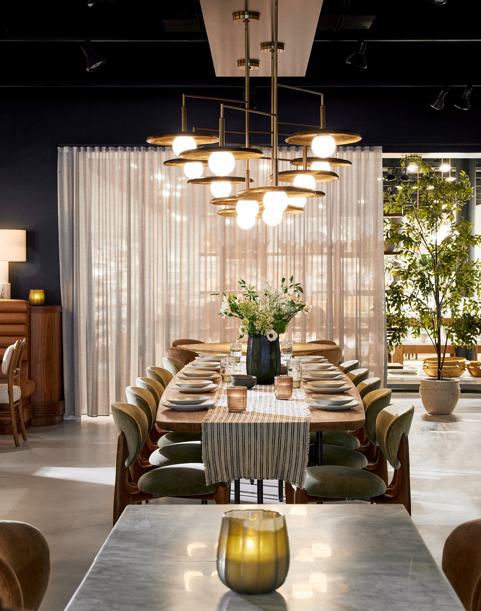 a dining room with a chandelier and table set with plates and flowers