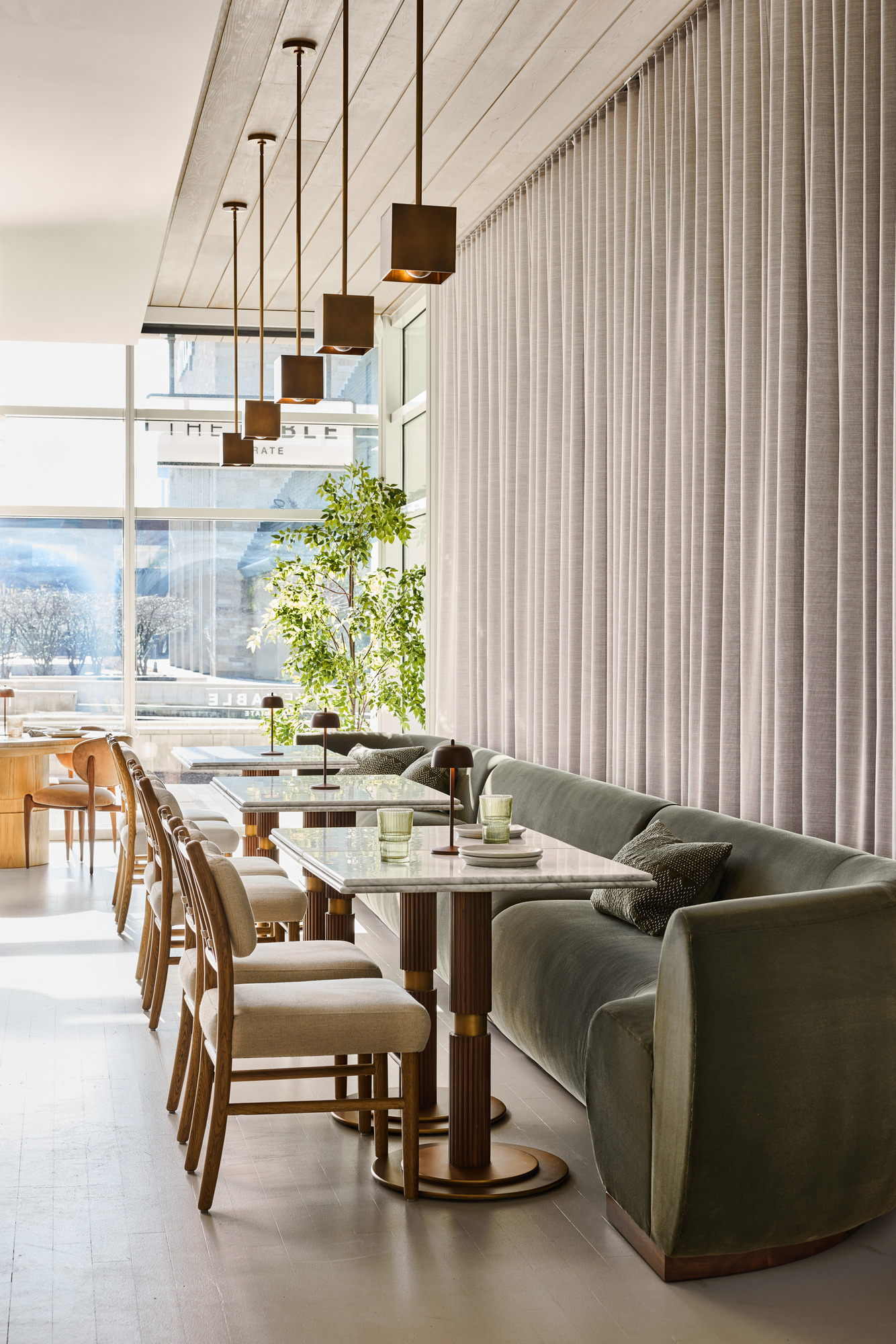 a long table with chairs and a couch in a room with curtains