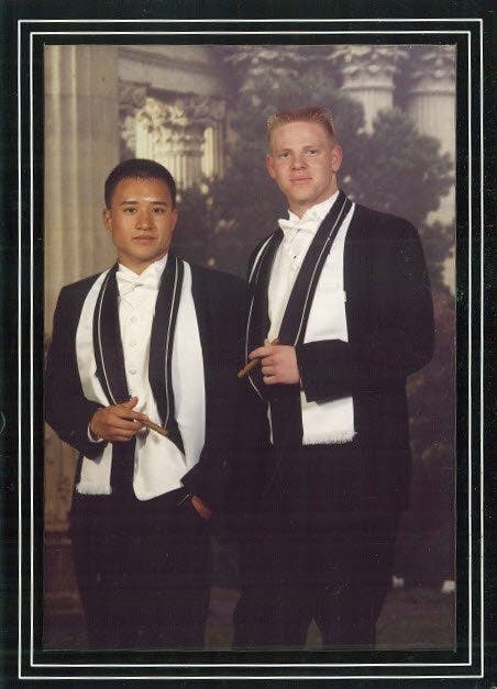 a man wearing a suit and tie standing next to a window