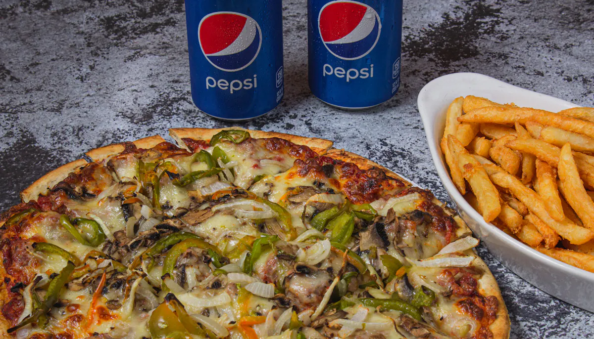 a pizza next to two cans of soda