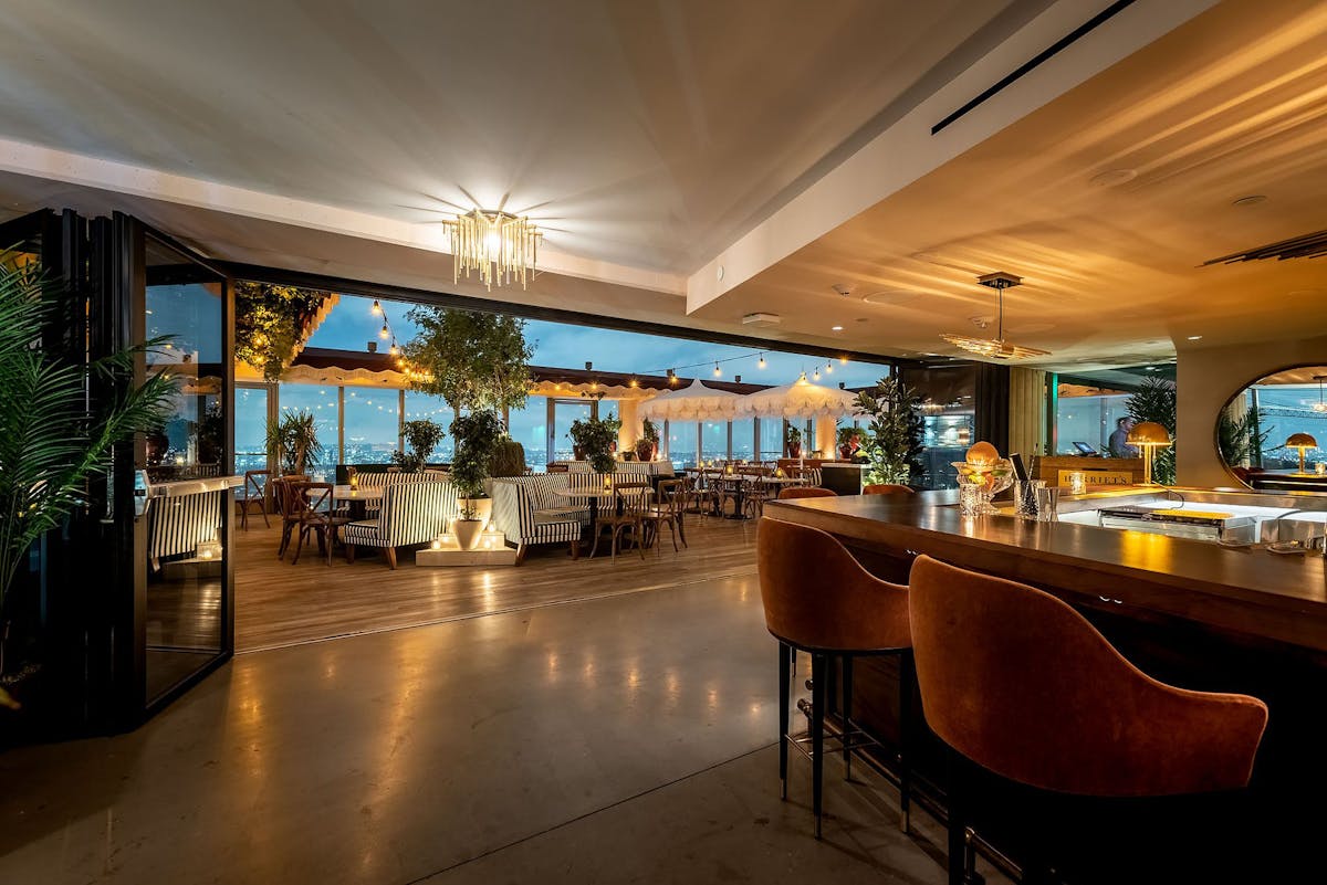 Gracias Madre - A tattooed barman selecting a bottle from a fully stocked bar in Hollywood.