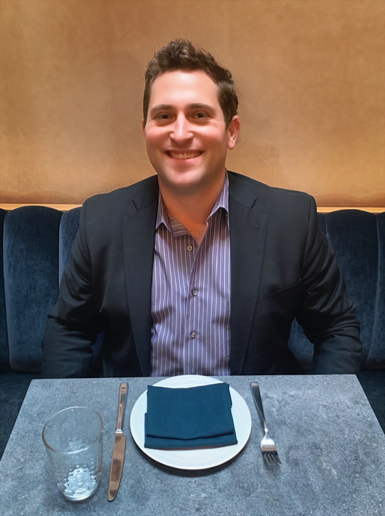 A man seated at a table, enjoying a meal from a plate in front of him.