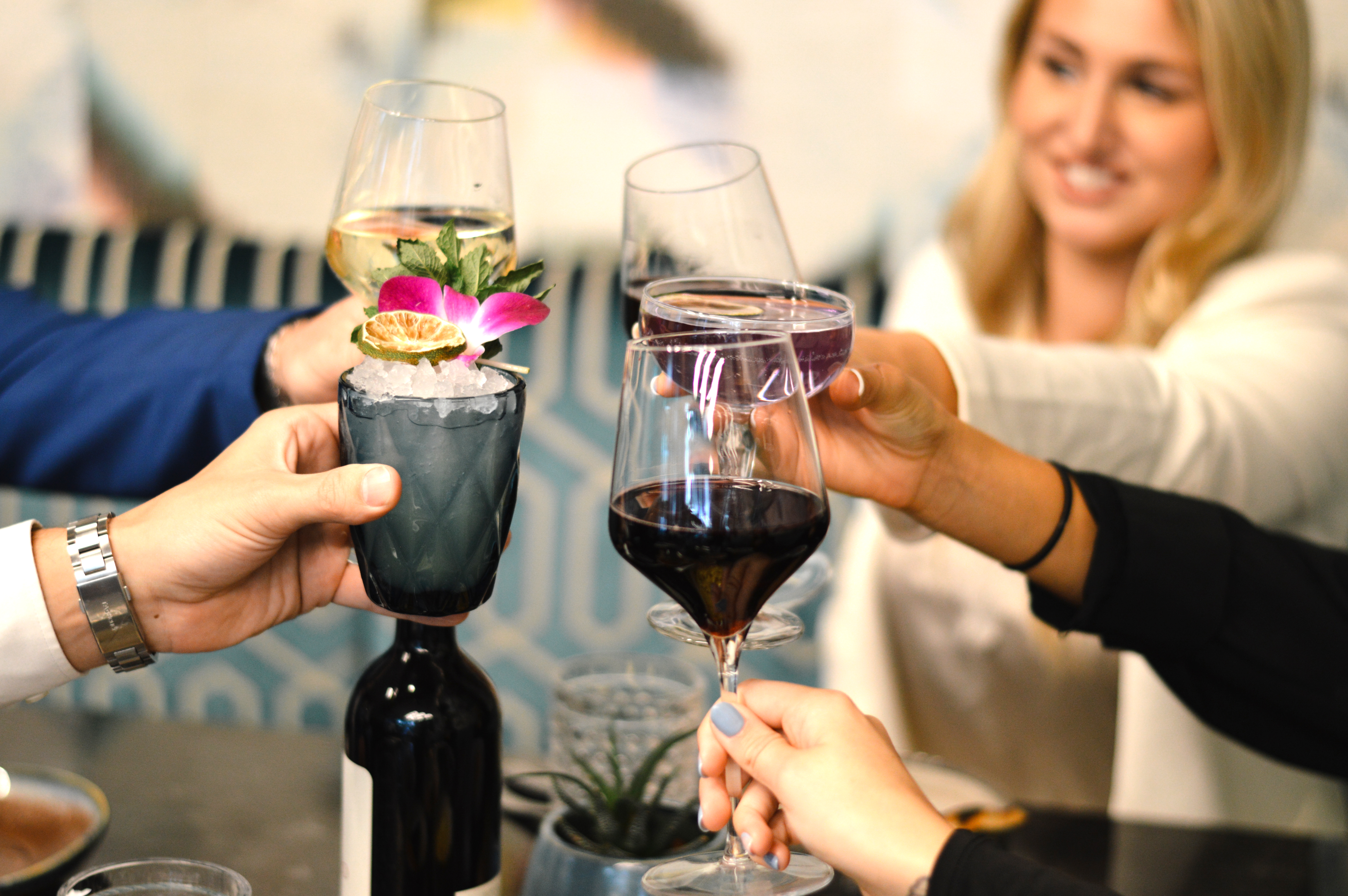 Friends toasting signature drinks over a marble bar top.