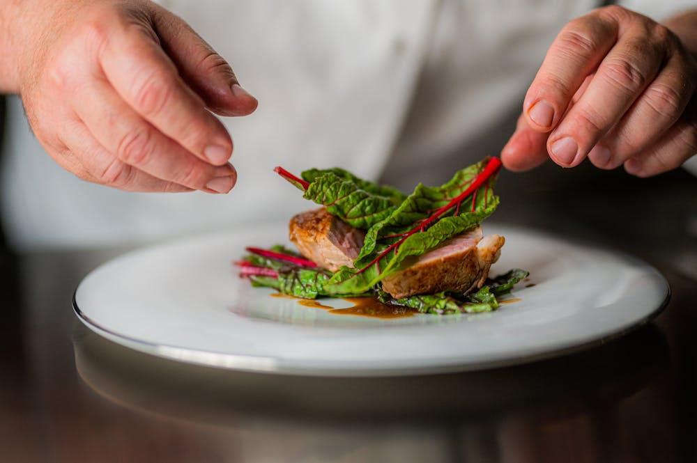 a hand holding a fork with a plate of food