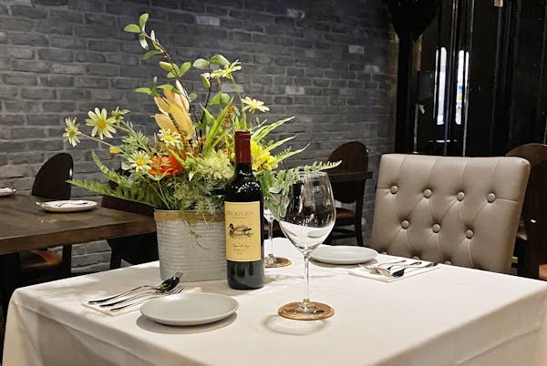 a vase of flowers on a table with wine glasses