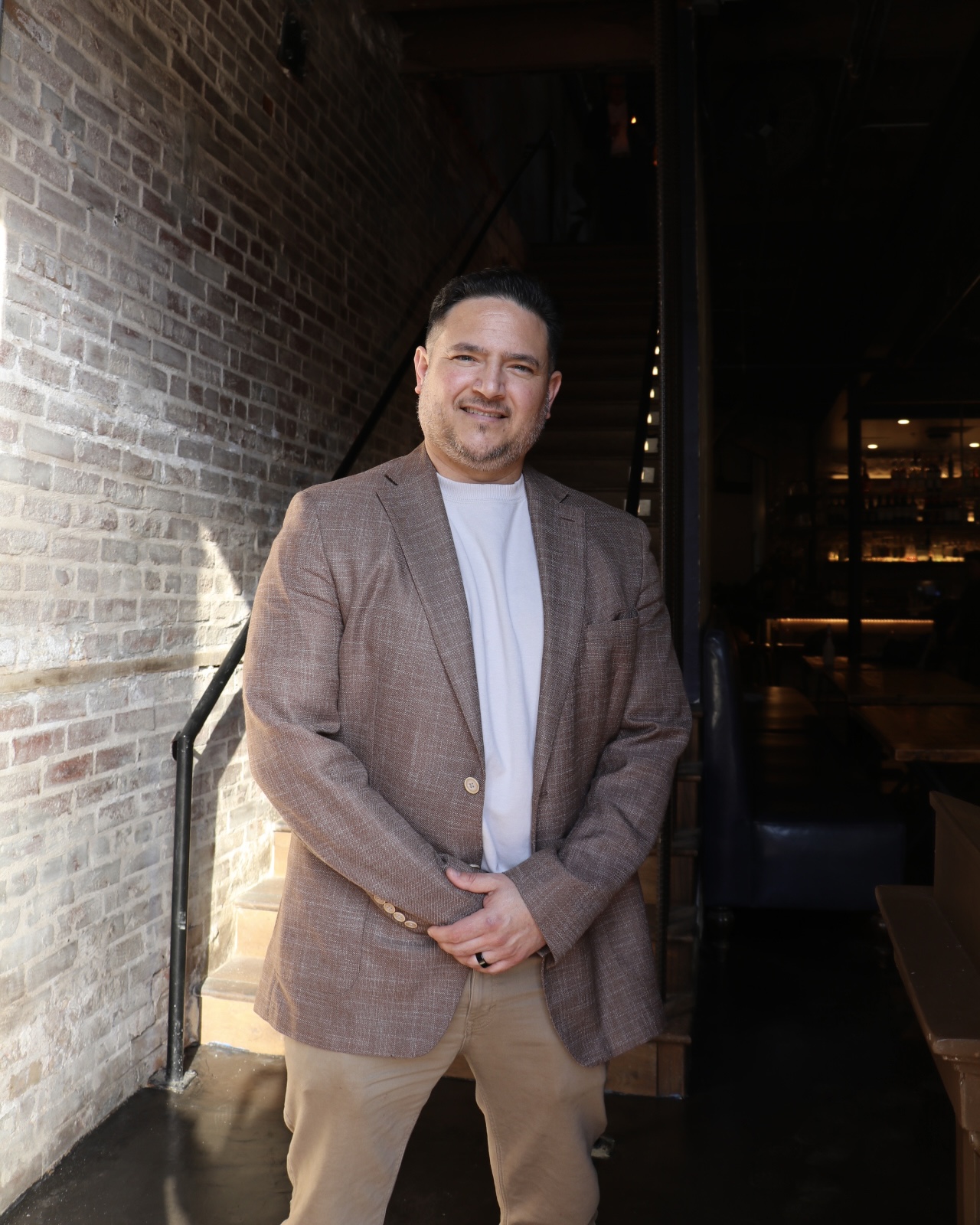 a man wearing a suit and tie standing in front of a building