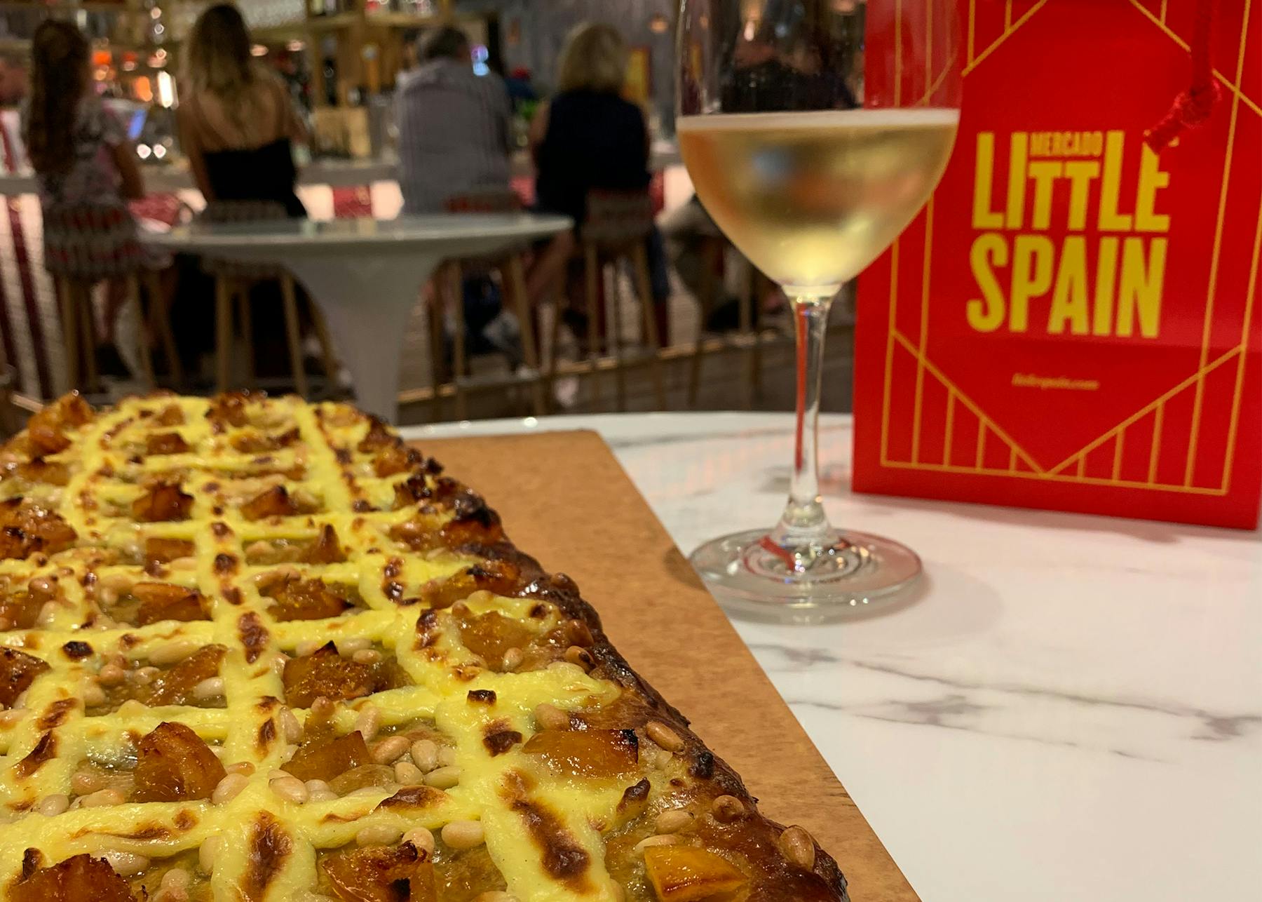 a pizza sitting on top of a table next to a glass of wine