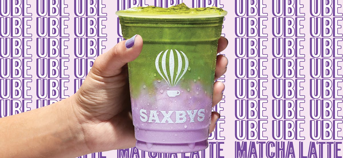 a hand holding an ube matcha latte