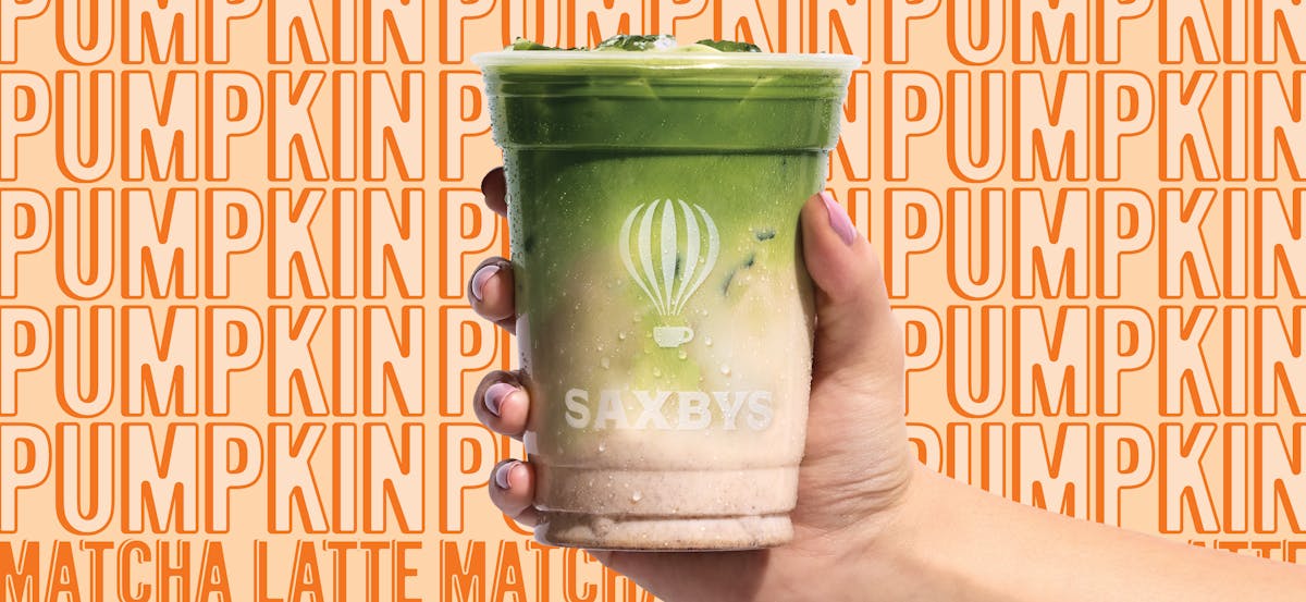a hand holding a pumpkin matcha latte