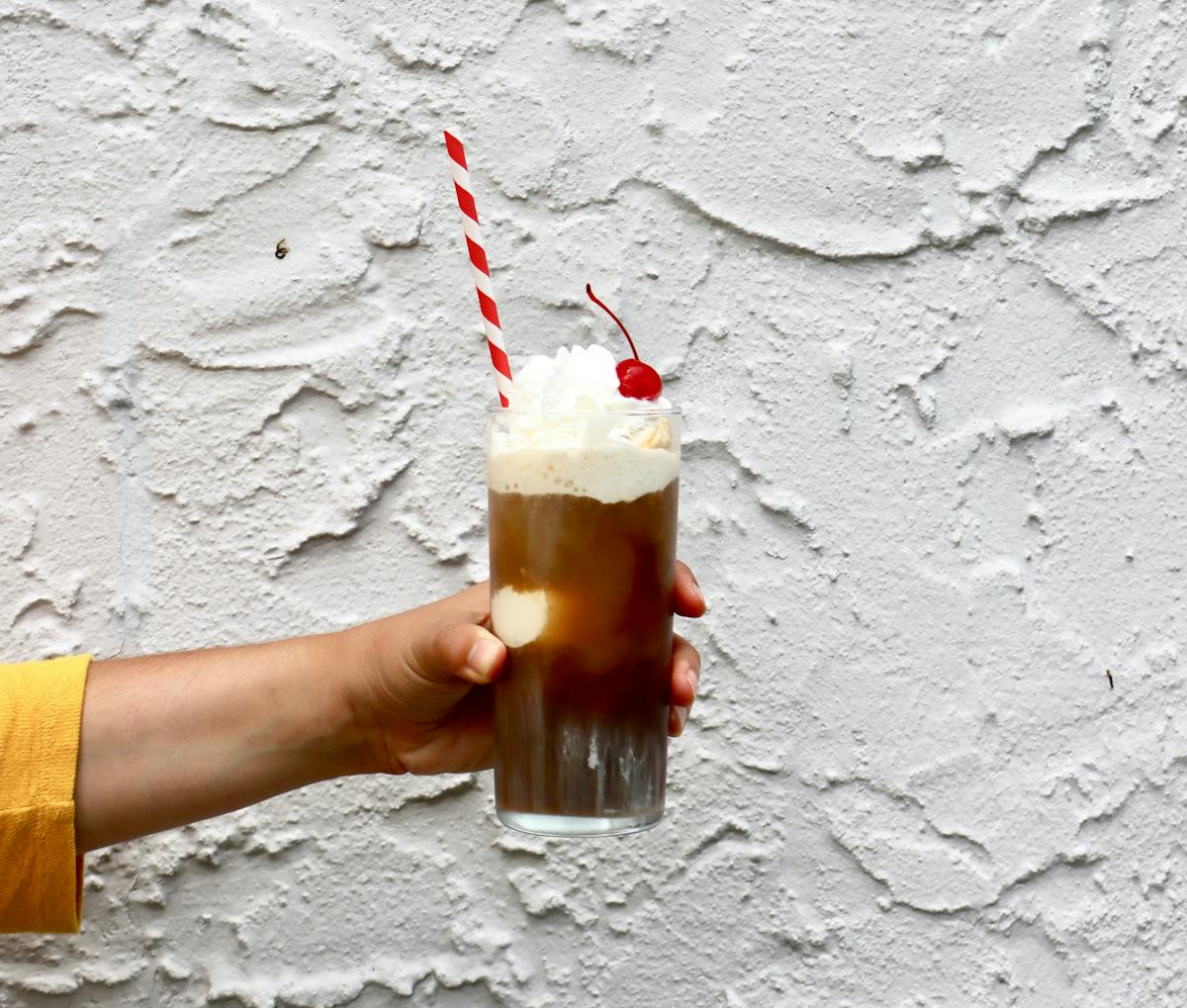 a hand holding a cold brew ice cream float