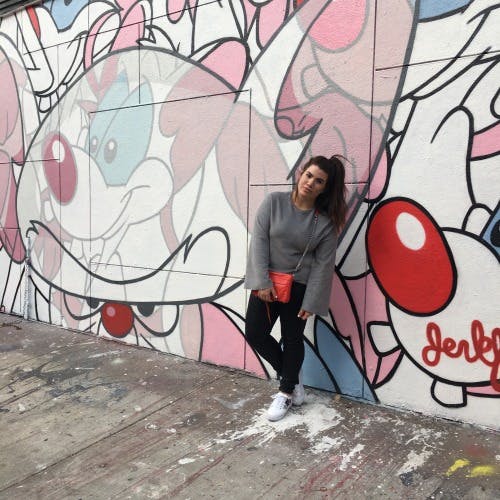 a woman standing for a pricture with a graffiti wall background