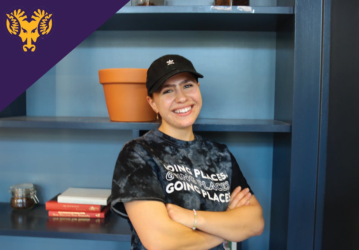 a girl wearing a hat smiling for the camera with her arms crossed