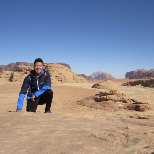 a man crouching in a desert for a picture