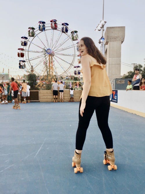 a woman standing laughing for the camera with an amusement park as the background