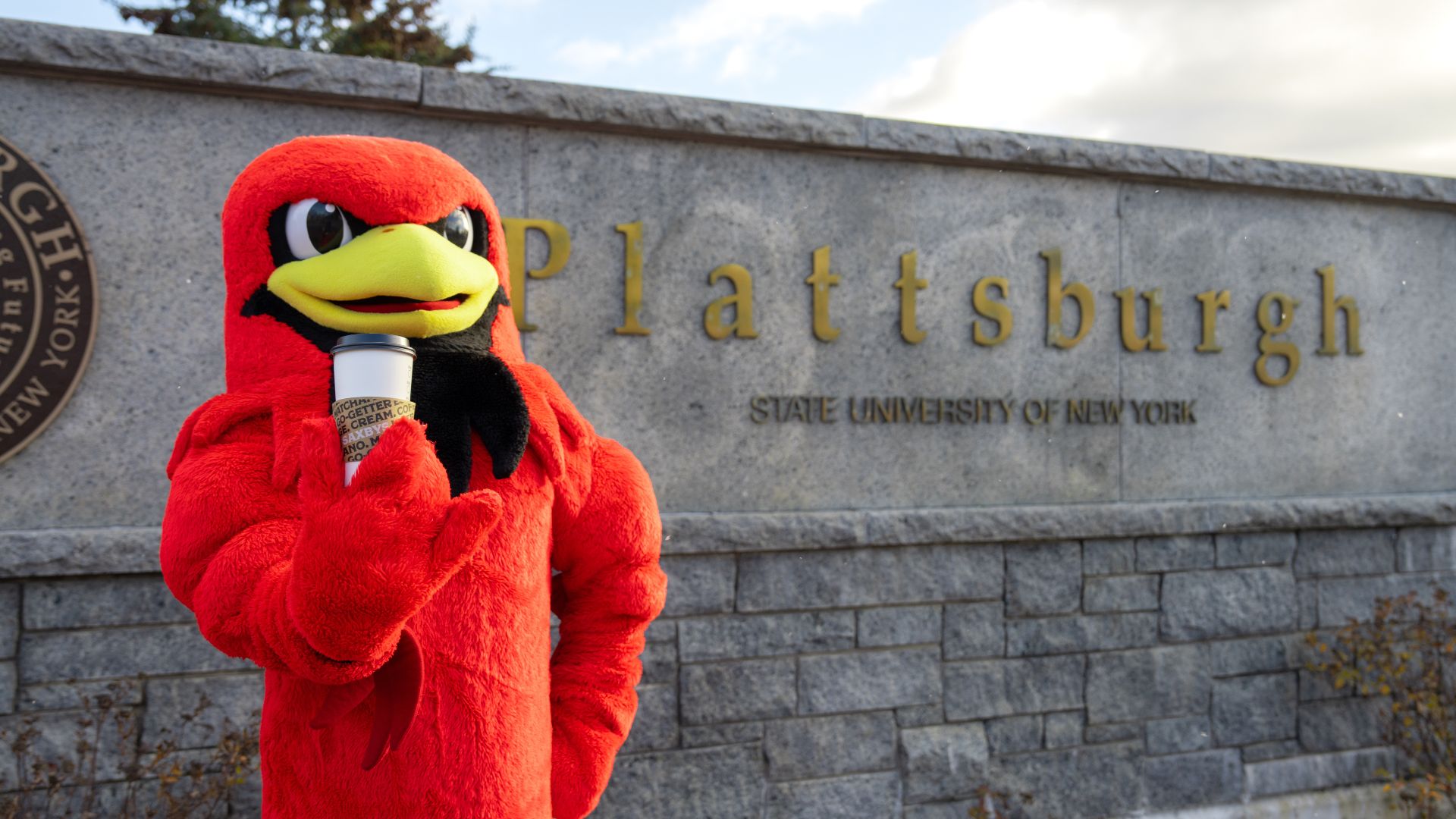 a mascot holding a coffee cup