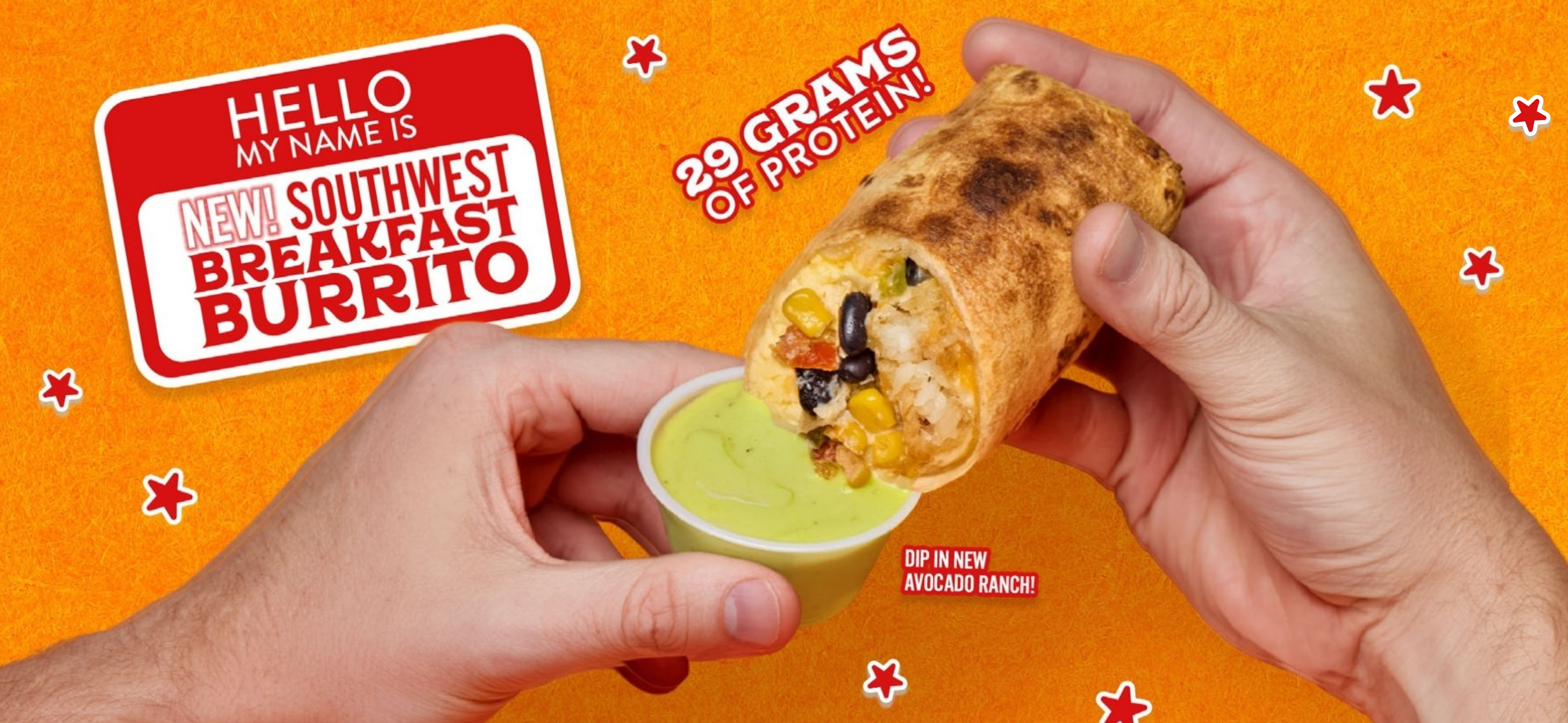 a person holding a burrito with a cup of sauce