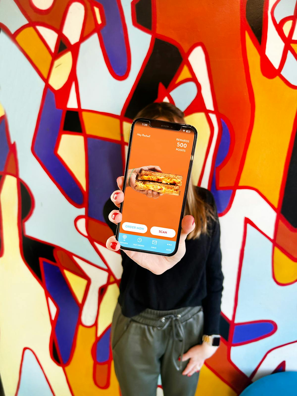 a hand holding a phone with the saxbys app open