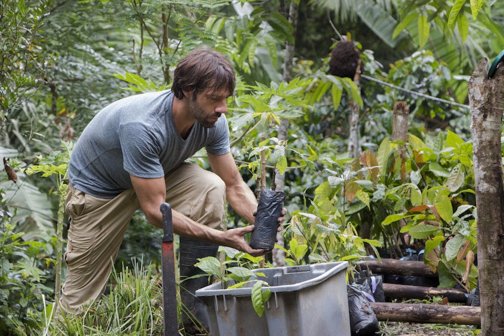 a man standing next to a banana tree