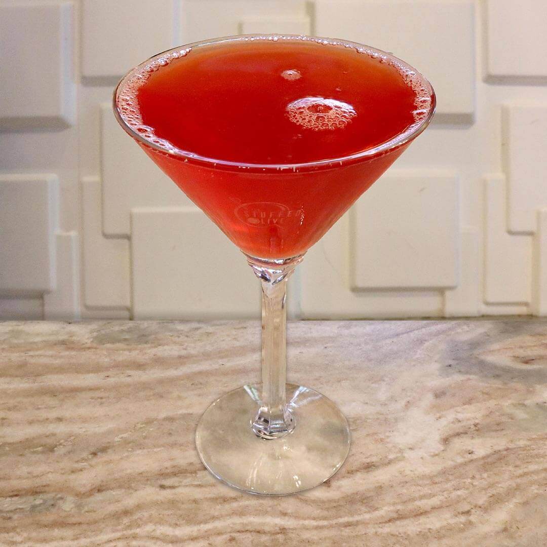 A deep, clear pomegranate red cocktail served in a chilled glass.