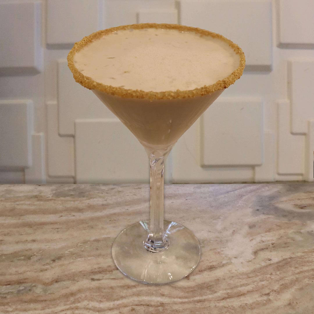 A creamy, pale yellow cocktail with a thick caramel and crushed graham cracker rim.