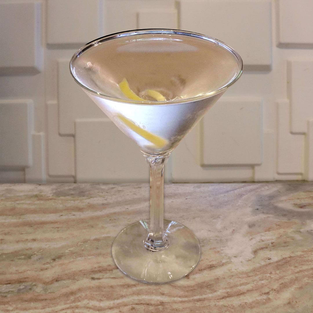 A crystal clear cocktail, elegantly garnished with two thin lemon twists.
