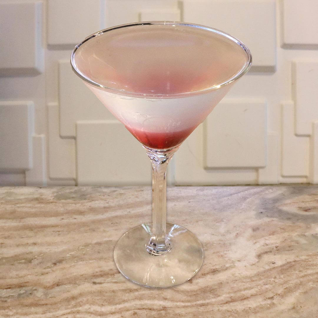 A layered cocktail featuring a clear top and a vibrant red layer at the bottom of the glass.