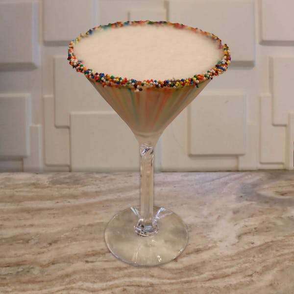 Cake Vodka, Dr. Mc Gillicuddy’s Vanilla, White Chocolate Liqueur, and Splash of Cream. Garnished with A Rainbow Sprinkle Rim