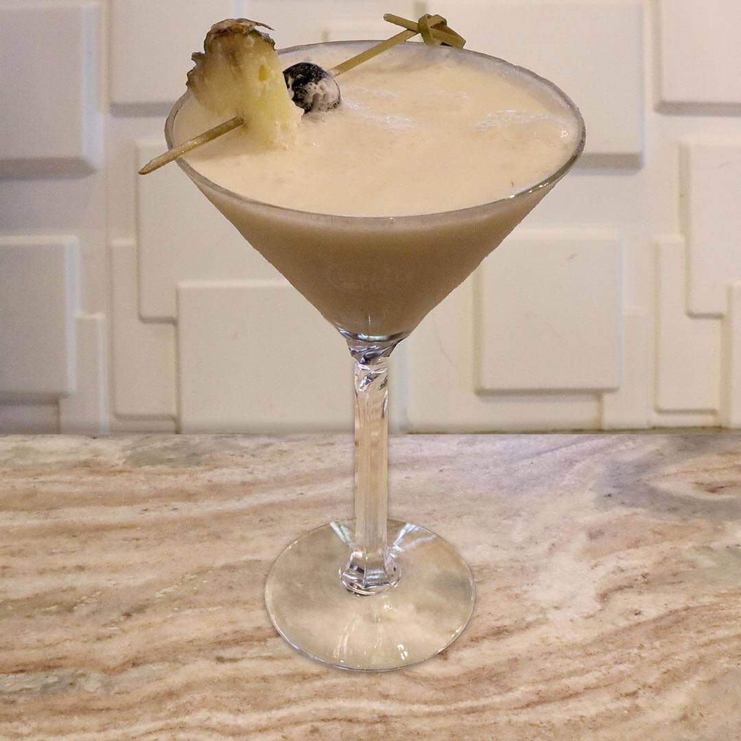A creamy tan frozen tropical cocktail garnished with a pineapple wedge.