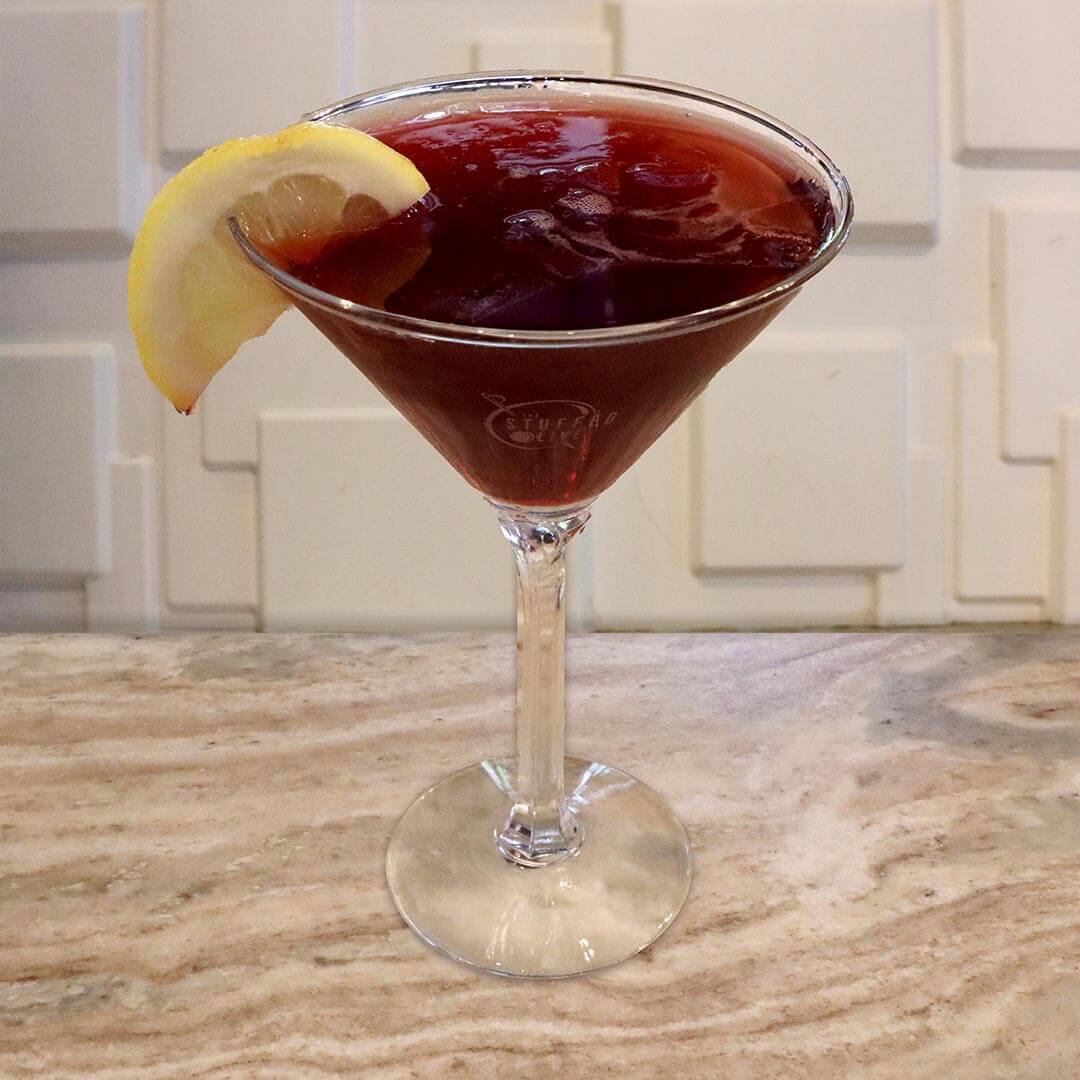 A deep red, vibrant raspberry cocktail garnished with a fresh lemon wedge.
