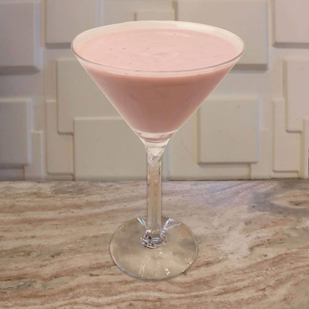 A creamy, opaque pink cocktail served in a classic glass resting on a marble surface.
