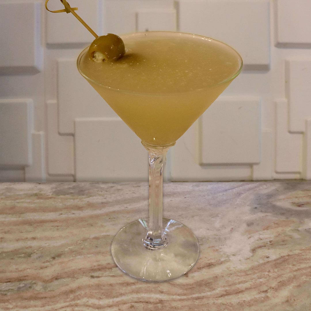 A clear, spirit-forward cocktail served with a green pimento-stuffed olive garnish.