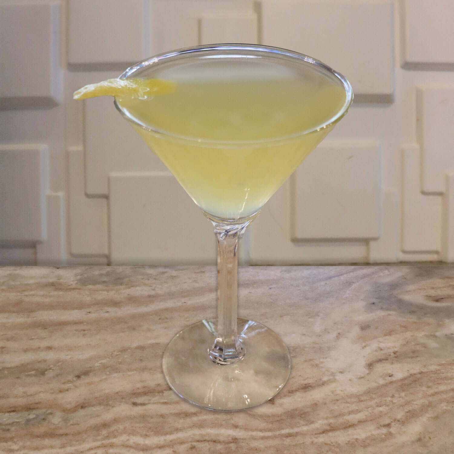 Premium Gin, Dry Vermouth, splash of orange juice. Garnished with a lemon twist
