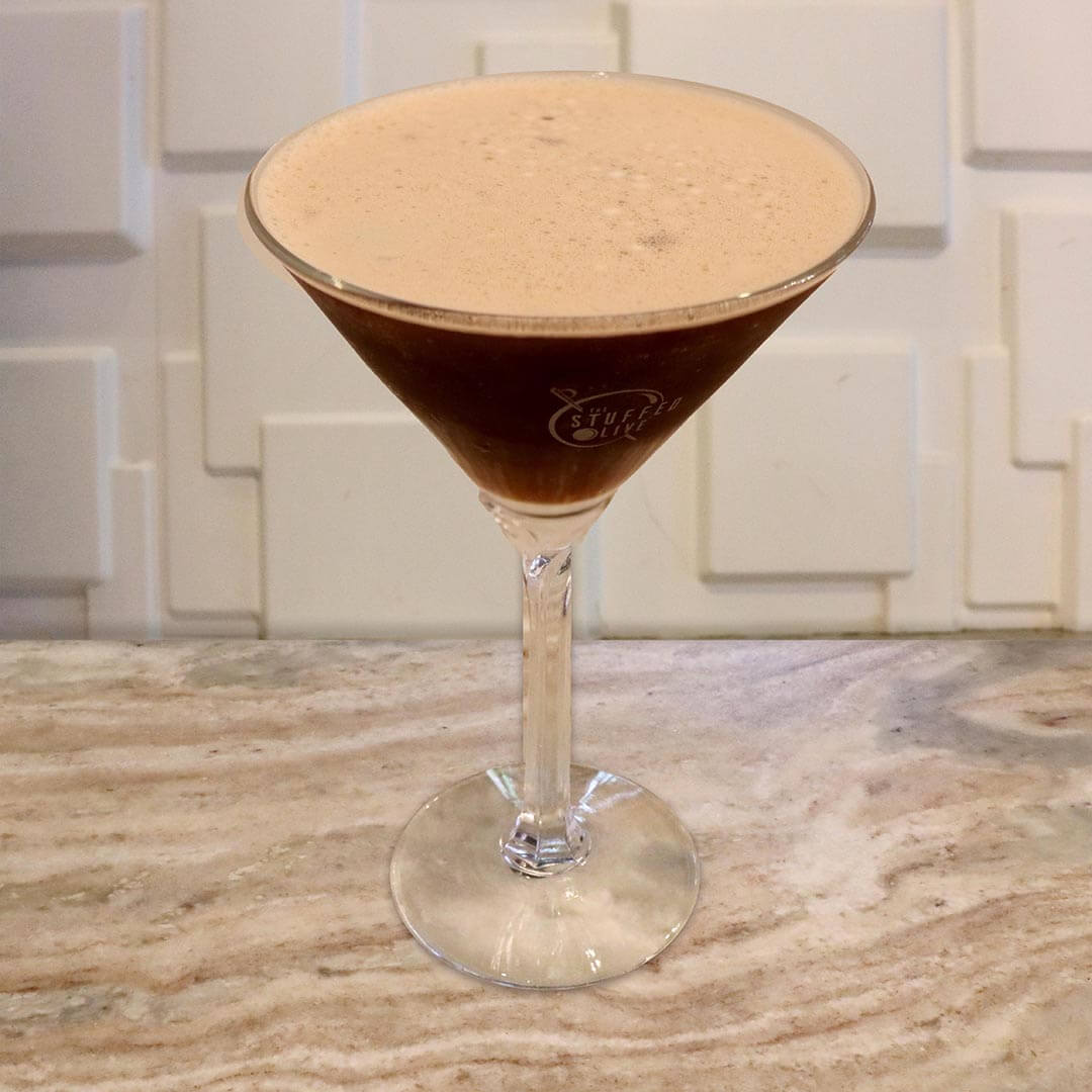 A dark, opaque purple cocktail with a foamy top.