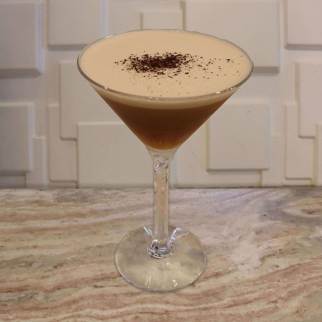 A dark coffee-colored beverage with light foam and a dusting of espresso powder.