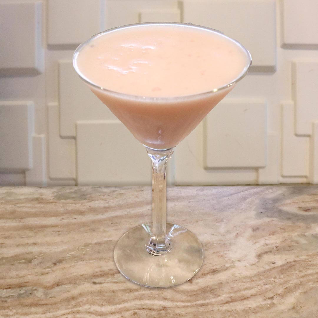 A creamy, opaque, pastel pink cocktail served in a chilled glass.