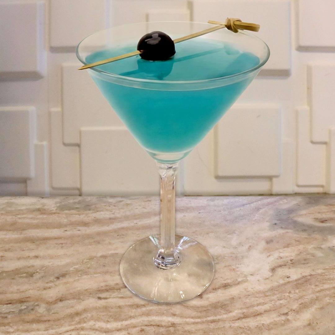 A bright, neon blue cocktail in a classic glass, garnished with a dark cherry on a bamboo skewer resting across the rim.