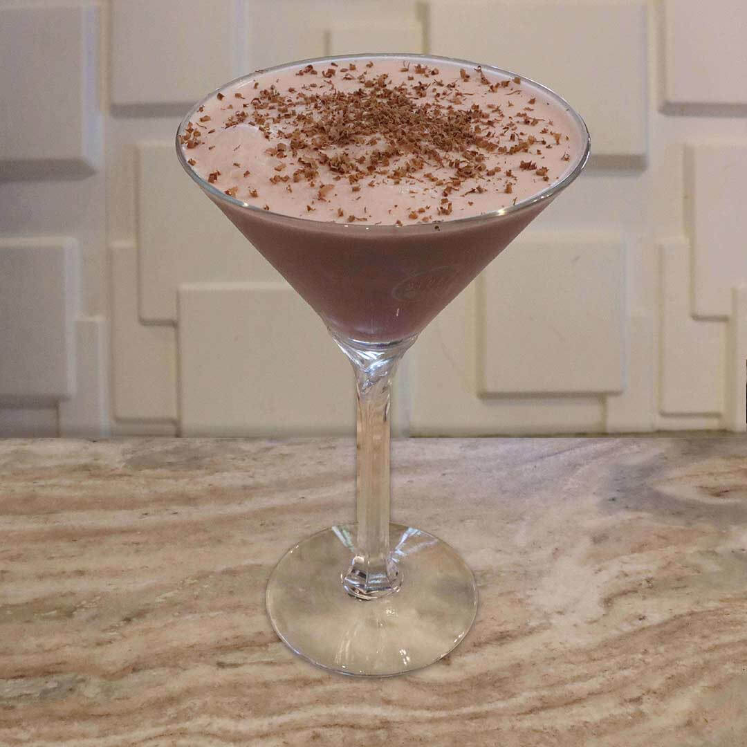 A creamy, pale pink cocktail topped with delicate chocolate shavings.