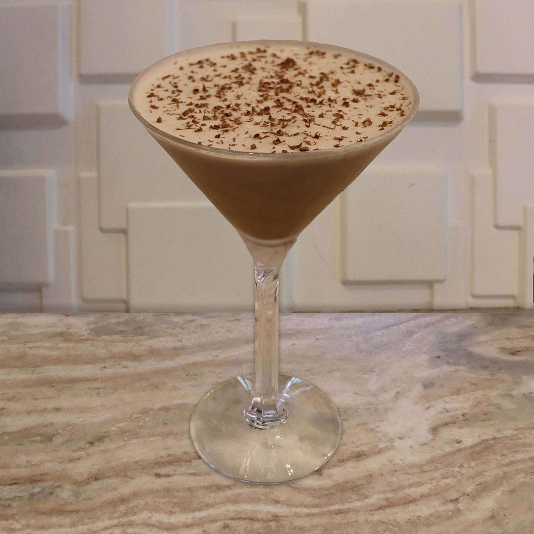 A creamy, dark brown chocolate cocktail topped with fresh, dark chocolate shavings.