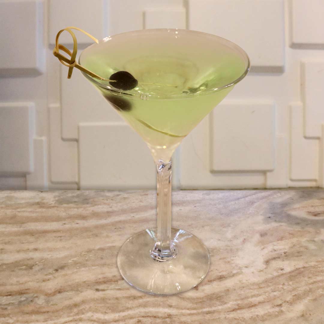 A bright, neon green cocktail served in a chilled glass, garnished with a dark cherry.