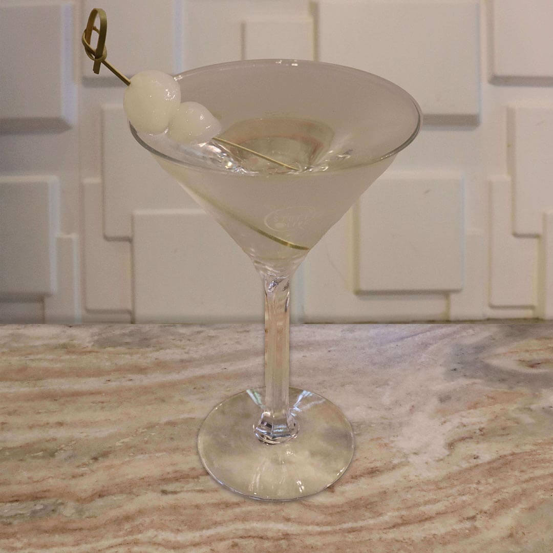 A clear, crisp cocktail garnished with a classic white cocktail onion.