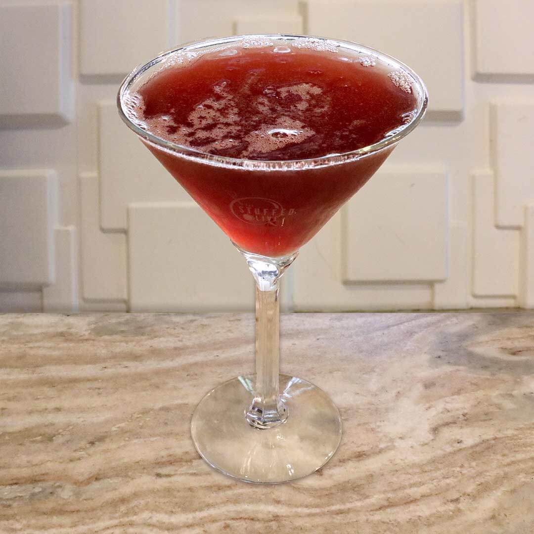 A rich, dark red berry cocktail served in a chilled glass.