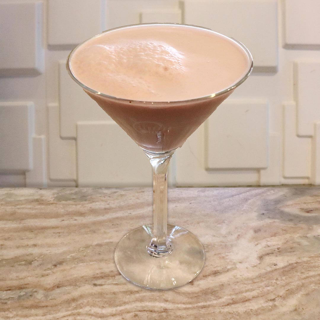 A creamy brown cocktail topped with a dollop of white foam.