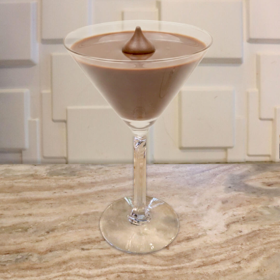 A creamy, smooth milk chocolate cocktail served in a classic glass, garnished with a chocolate kiss candy floating in the center.