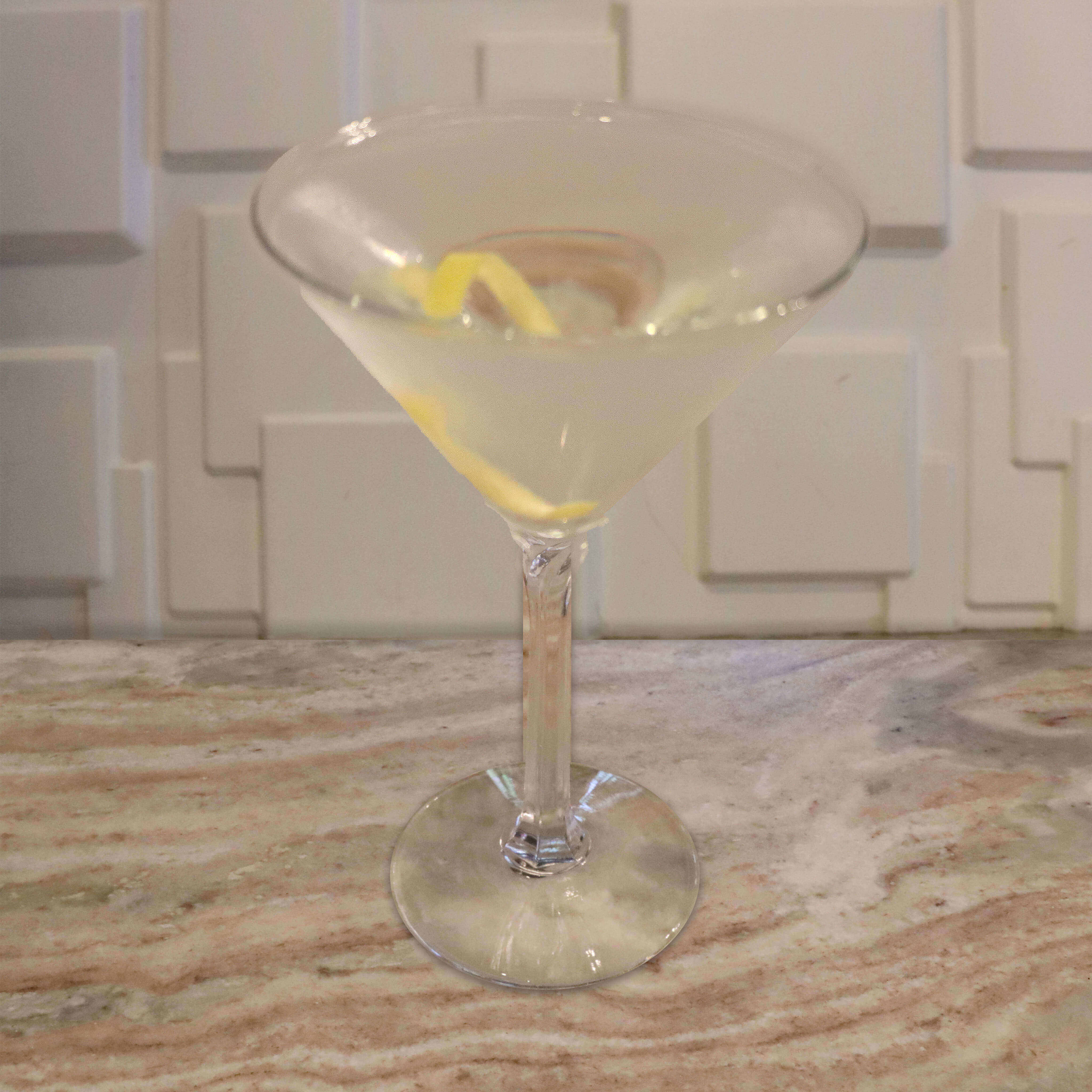 A crystal clear, ultra-dry cocktail garnished with a thin yellow lemon twist.