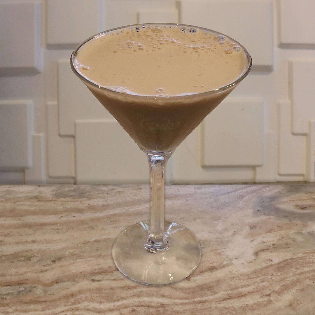 A creamy, light tan cocktail served in a chilled glass.