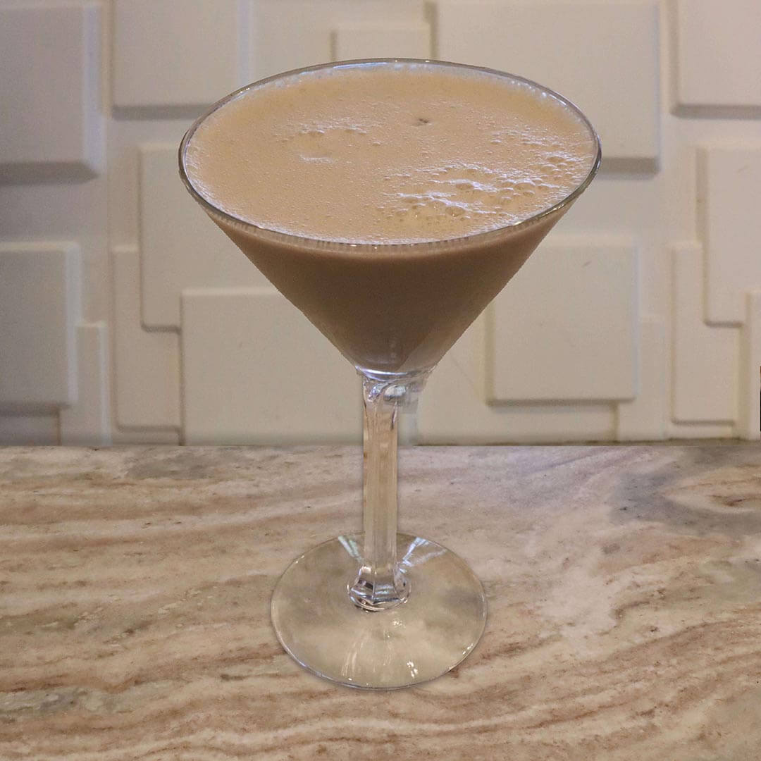 A creamy, light tan-pink chocolate raspberry cocktail served in a chilled glass.