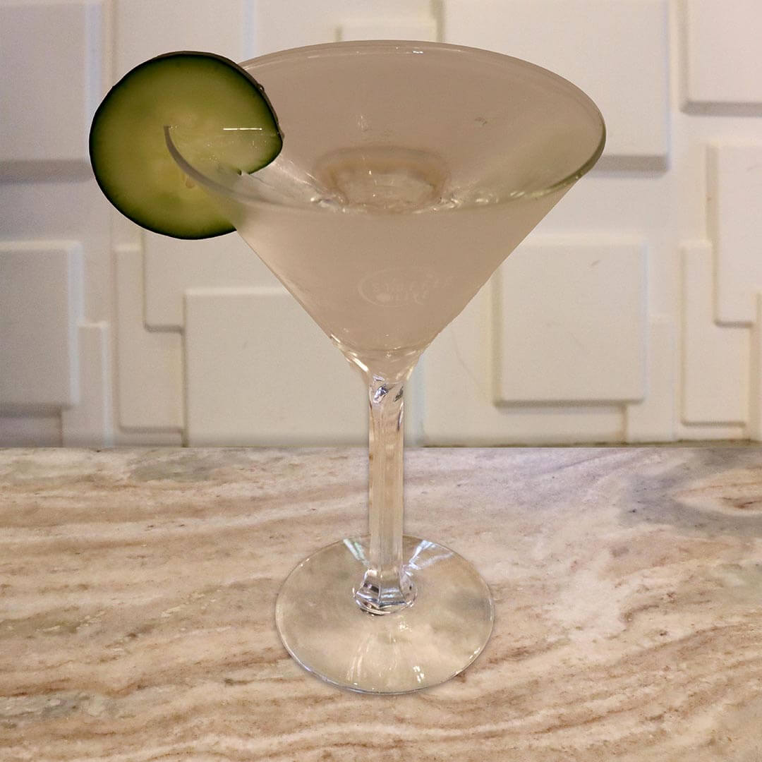 A clear, effervescent cocktail served in a chilled glass, garnished with a fresh cucumber slice.